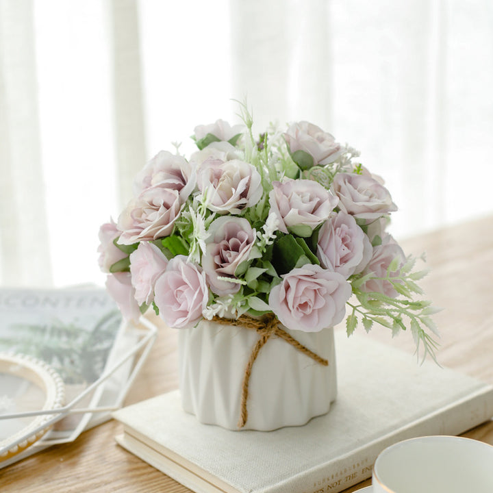 Seidenblumenarrangement in einem mit Schnur umwickelten Keramikpflanzer als Tischmittelpunkt