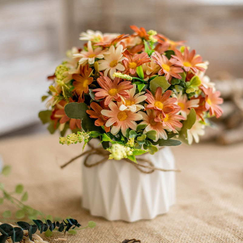 Seidenblumenarrangement in einem mit Schnur umwickelten Keramikpflanzer als Tischmittelpunkt
