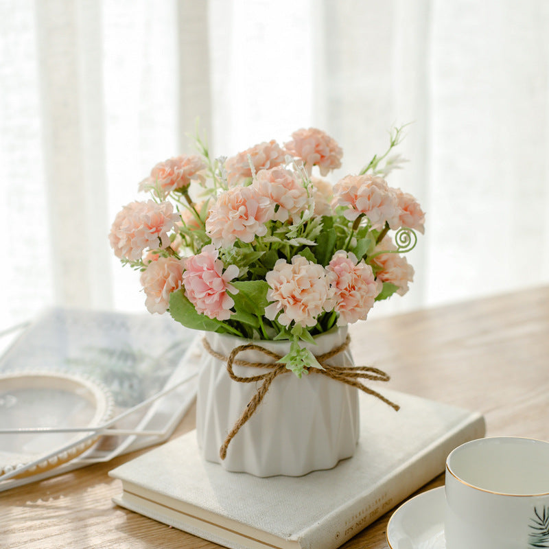Seidenblumenarrangement in einem mit Schnur umwickelten Keramikpflanzer als Tischmittelpunkt