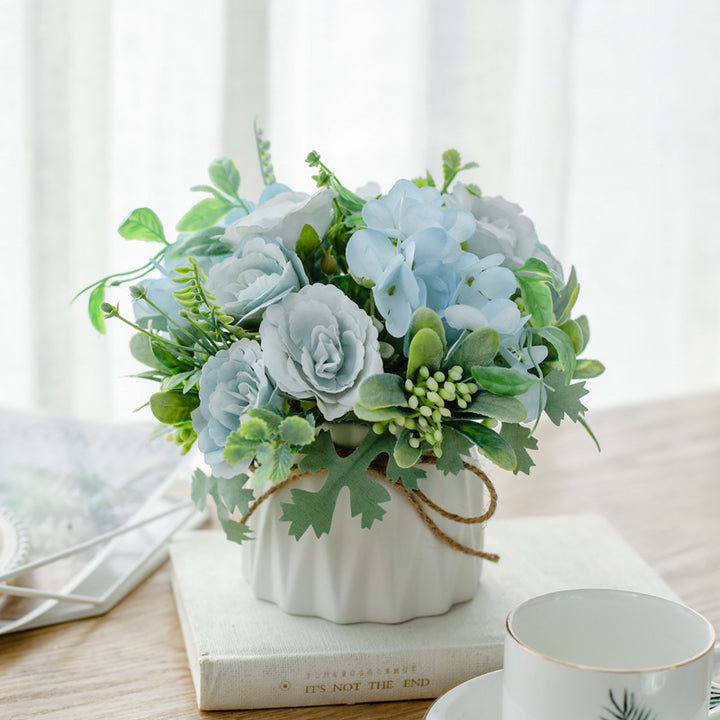 Seidenblumenarrangement in einem mit Schnur umwickelten Keramikpflanzer als Tischmittelpunkt