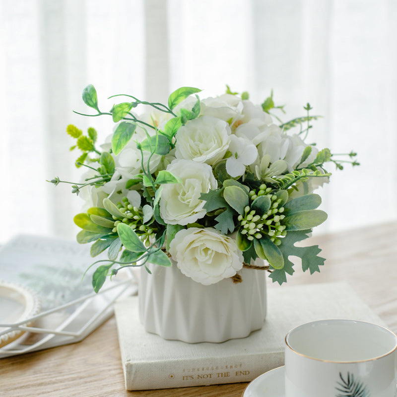 Seidenblumenarrangement in einem mit Schnur umwickelten Keramikpflanzer als Tischmittelpunkt