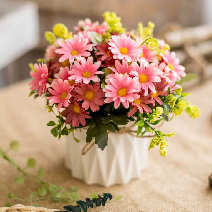 Seidenblumenarrangement in einem mit Schnur umwickelten Keramikpflanzer als Tischmittelpunkt