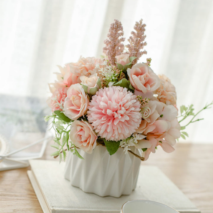 Seidenblumenarrangement in einem mit Schnur umwickelten Keramikpflanzer als Tischmittelpunkt