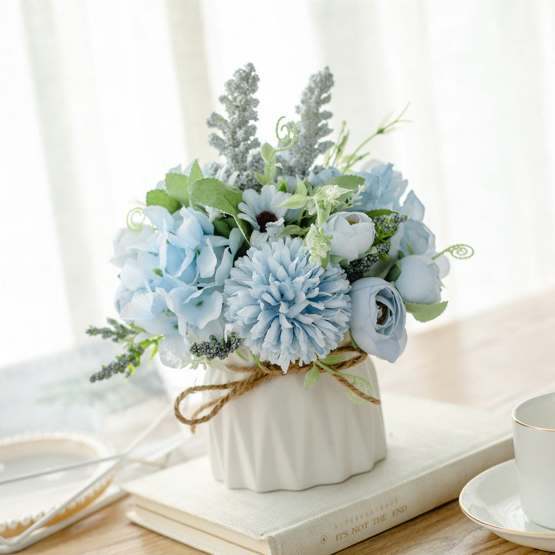 Seidenblumenarrangement in einem mit Schnur umwickelten Keramikpflanzer als Tischmittelpunkt