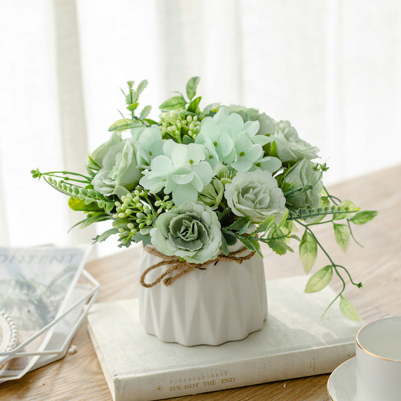 Seidenblumenarrangement in einem mit Schnur umwickelten Keramikpflanzer als Tischmittelpunkt