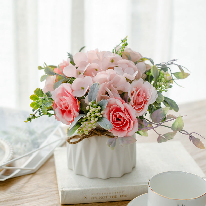 Seidenblumenarrangement in einem mit Schnur umwickelten Keramikpflanzer als Tischmittelpunkt