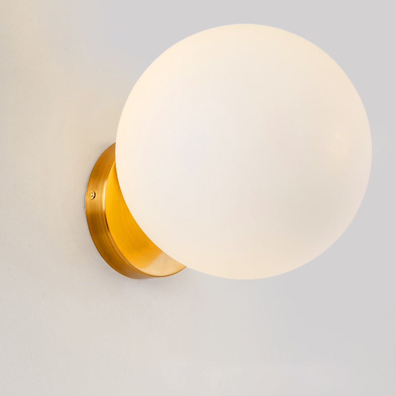 Runde Wandleuchte mit mattweißer Glaskugel und goldener Wandhalterung