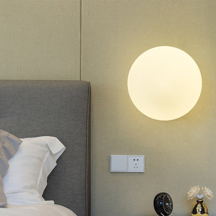 Kugel-Wandleuchte mit weichem Licht in modernem Schlafzimmer über Nachttisch
