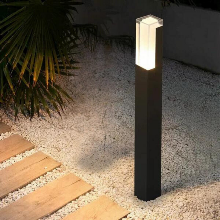 Moderne Pollerleuchte mit rechteckigem Lichtgehäuse auf Wegplatten im Außenbereich