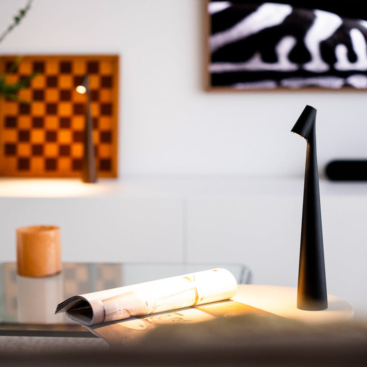 Schwarz glänzende LED-Tischlampe auf Couchtisch mit Schachbrett im Hintergrund