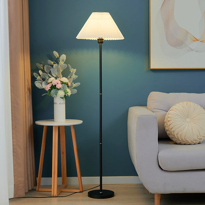Weiße Stehlampe mit Plisseeschirm in Wohnzimmer mit blauer Wand und Deko