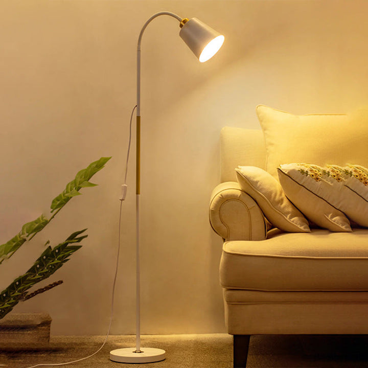 Weiß-goldene Stehlampe mit gebogenem Hals neben Sofa und Pflanze