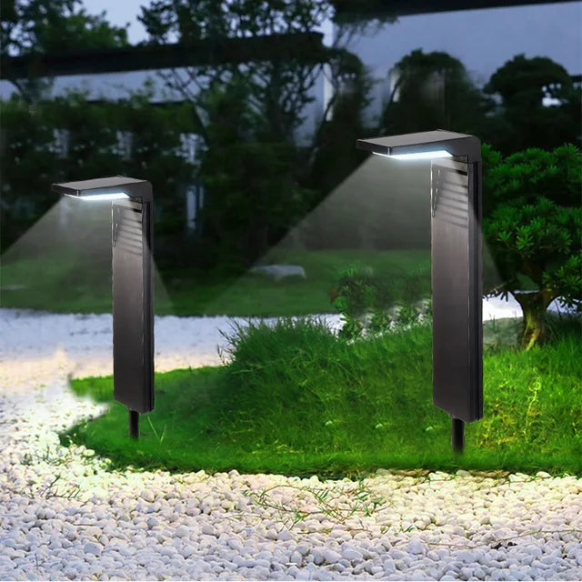 LED-Solarlampen mit flachem Kopf auf Kiesweg zwischen Pflanzen im Garten