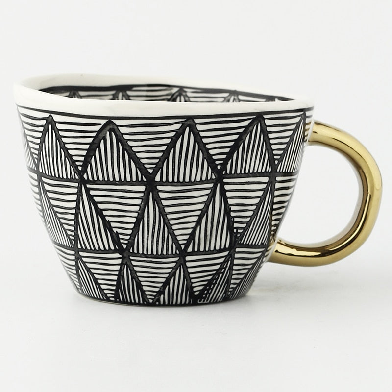Tasse mit abstraktem geometrischen Muster und goldenem Henkel