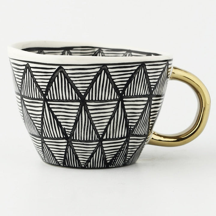 Tasse mit abstraktem geometrischen Muster und goldenem Henkel