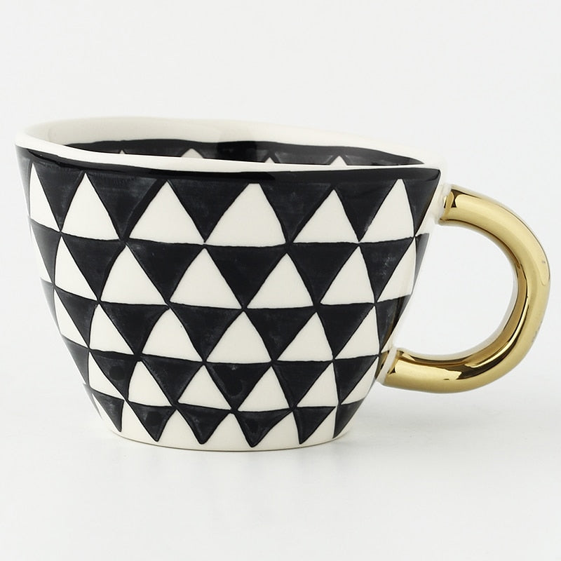 Tasse mit abstraktem geometrischen Muster und goldenem Henkel