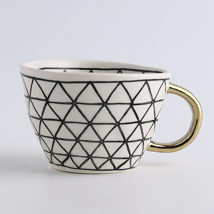 Tasse mit abstraktem geometrischen Muster und goldenem Henkel