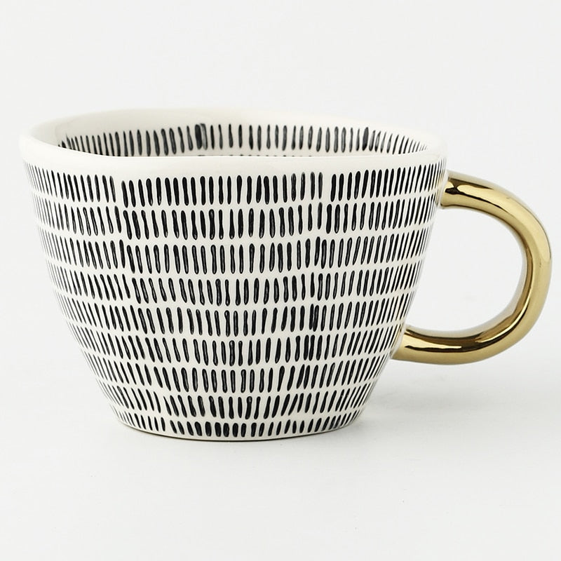 Tasse mit abstraktem geometrischen Muster und goldenem Henkel