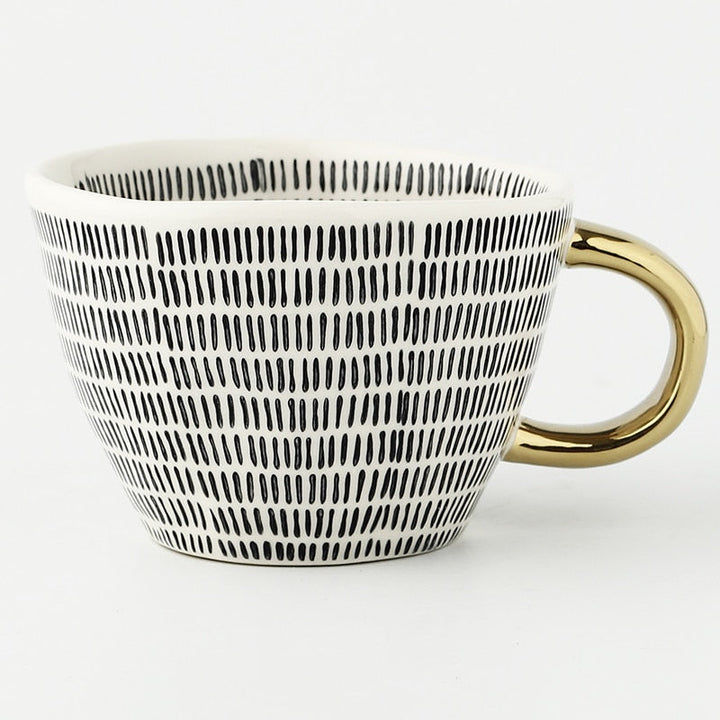 Tasse mit abstraktem geometrischen Muster und goldenem Henkel