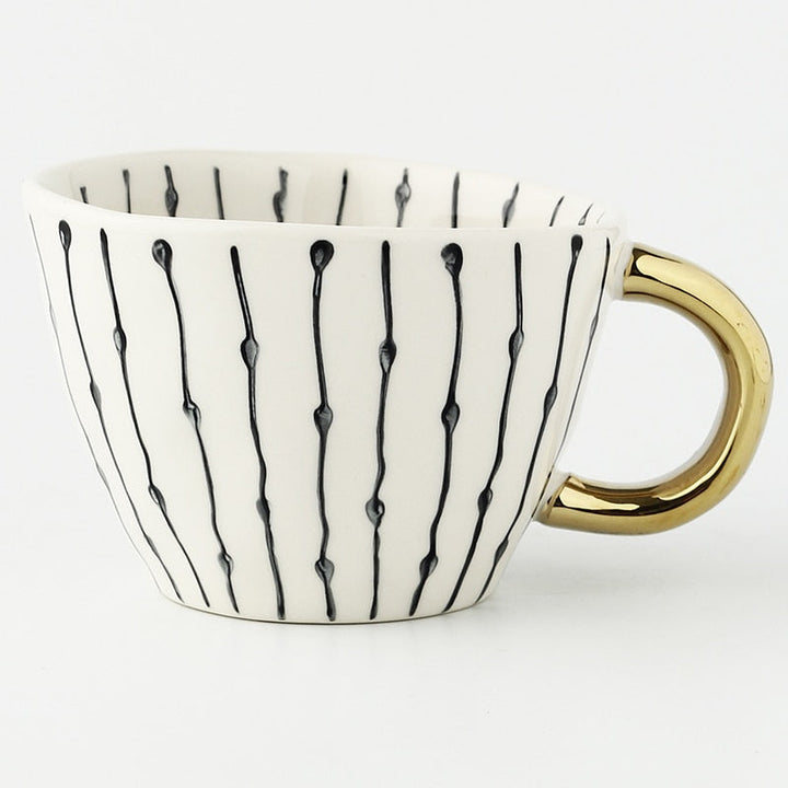 Tasse mit abstraktem geometrischen Muster und goldenem Henkel