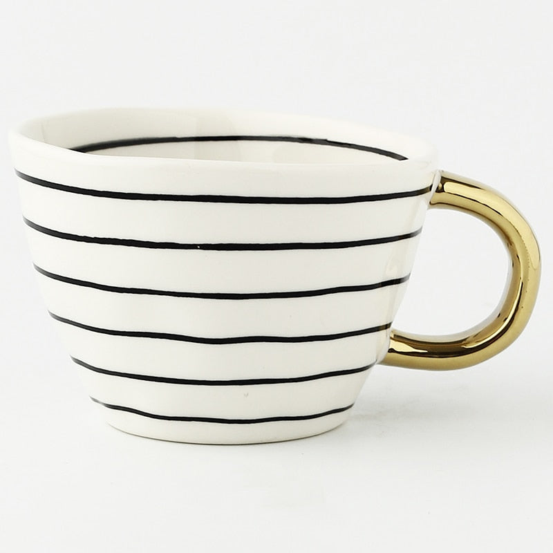 Tasse mit abstraktem geometrischen Muster und goldenem Henkel