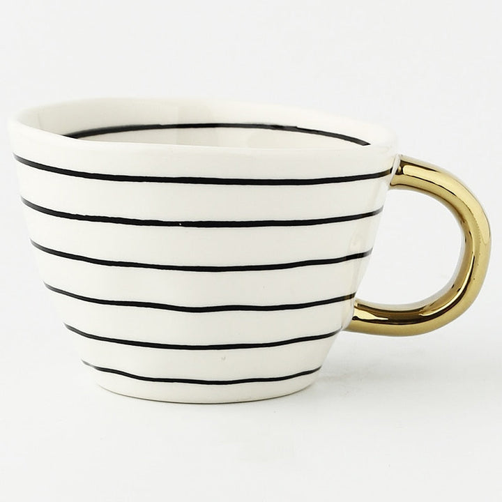 Tasse mit abstraktem geometrischen Muster und goldenem Henkel