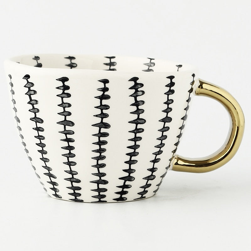Tasse mit abstraktem geometrischen Muster und goldenem Henkel