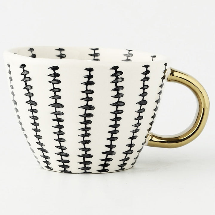 Tasse mit abstraktem geometrischen Muster und goldenem Henkel