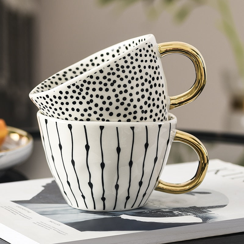 Tasse mit abstraktem geometrischen Muster und goldenem Henkel