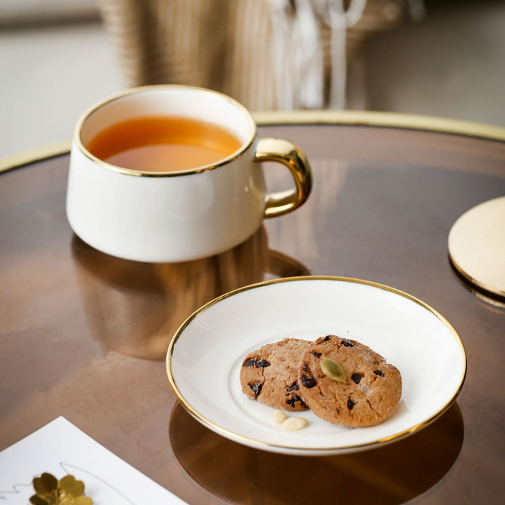 Elegante Porzellan-Tasse mit Untertasse und skulpturellem Goldhenkel