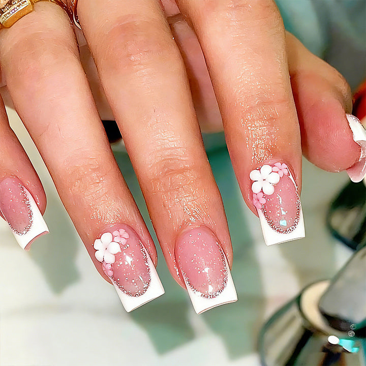 Kunstnagelset mit elegantem French-Tipp und filigranen Blütenverzierungen Karnz