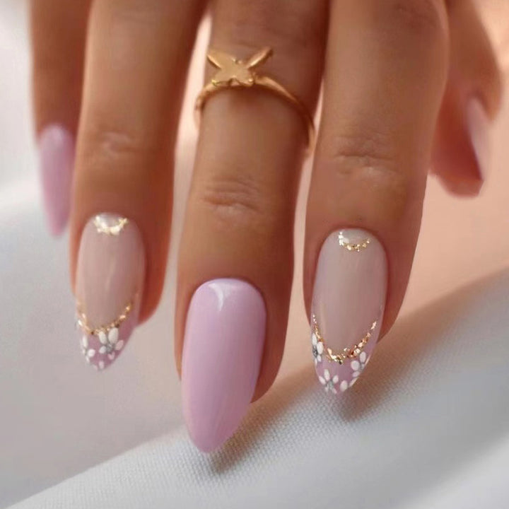 Elegante Kunstnägel mit floralem Design und goldenen Akzenten Karnz
