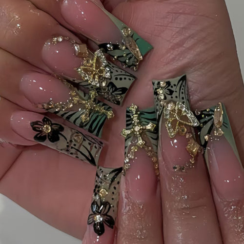 Künstlerisches Stiletto-Nageldesign mit floralen Akzenten und Edelsteinen Karnz