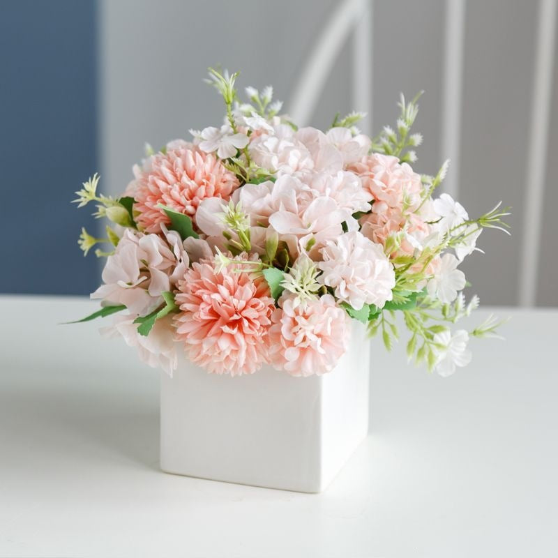 Lebensechte Blumenarrangement in dekorativem quadratischen Pflanzgefäß