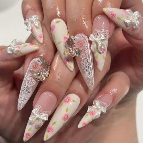 Kunstvolle Stiletto-Nägel mit floralen Akzenten und Glitzerakzenten Karnz