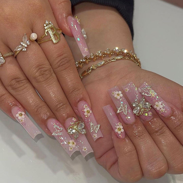 Kunstvolle Nagelverlängerungen mit Glitzer und floralen Akzenten Karnz