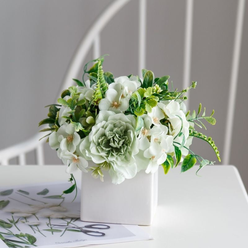 Lebensechte Blumenarrangement in dekorativem quadratischen Pflanzgefäß