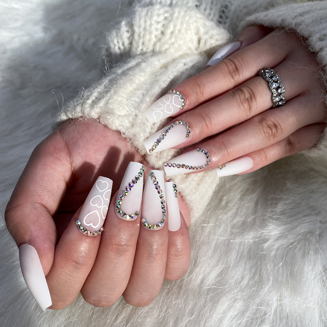 Kunstvolle Nagelverlängerungen mit Herzen-Design und Glitzerakzenten Karnz