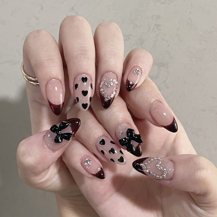 Künstlerische Stiletto-Nagelverlängerungen mit Herz- und Schleifenakzenten Karnz
