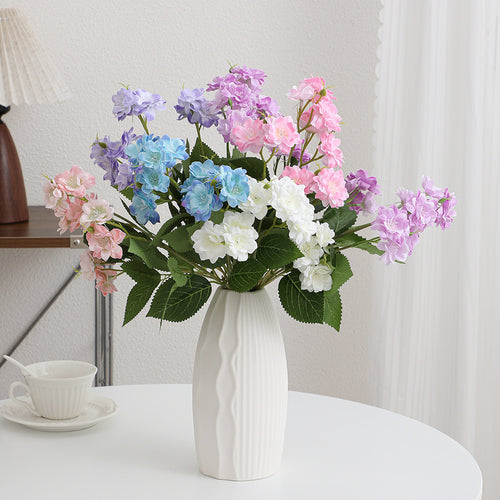 Kunstblumenarrangement mit zarten weißen Blüten Karnz