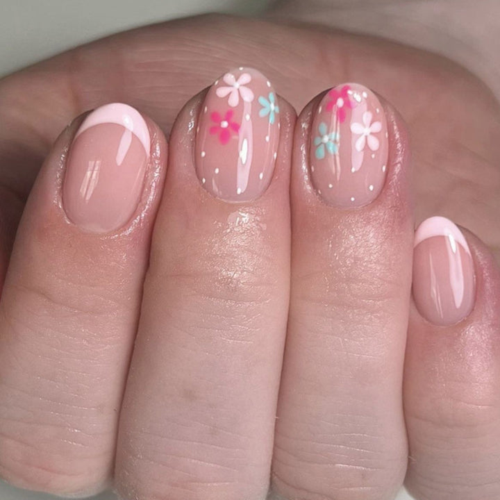 Kunstvolle Nagelverlängerungen mit bunten Blütenmotiven und Glitzer Karnz