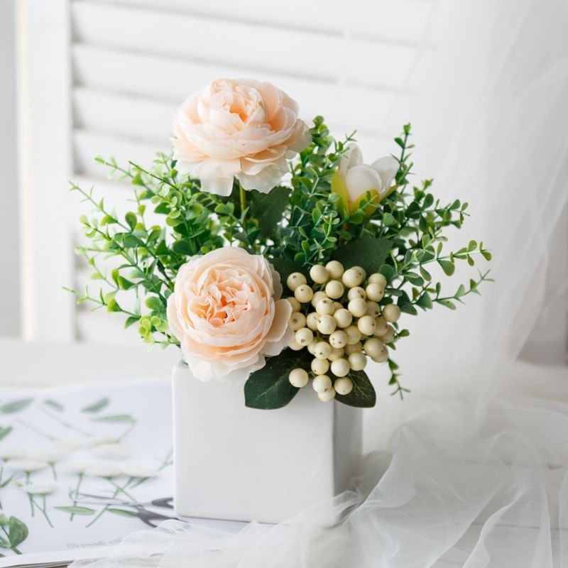 Lebensechte Blumenarrangement in dekorativem quadratischen Pflanzgefäß