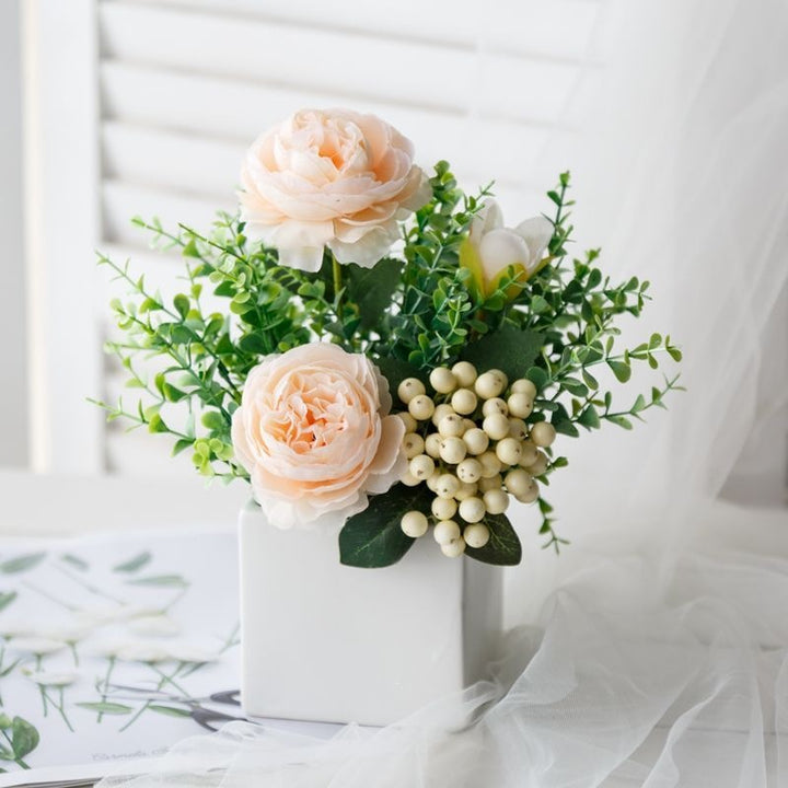 Lebensechte Blumenarrangement in dekorativem quadratischen Pflanzgefäß