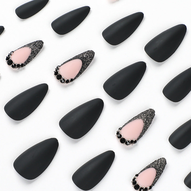 Kunstvolle Stiletto-Nägel mit elegantem Schwarz-Design und Glitzerakzenten Karnz