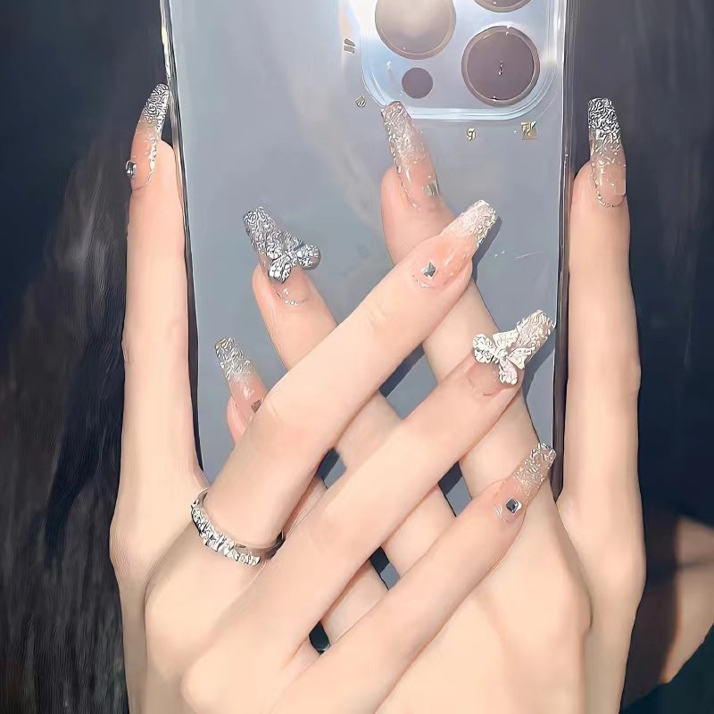 Kunstvolle Nagelkunst mit Schmetterlings- und Perlendetails Karnz