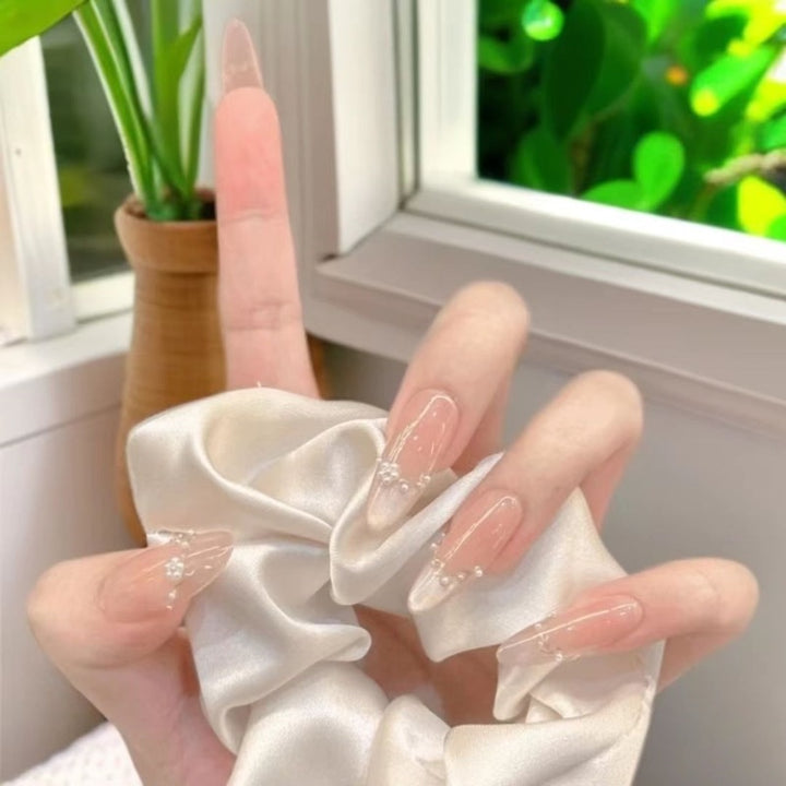 Dekorative Acryl-Nagelerweiterungen mit perlmuttartigen Akzenten