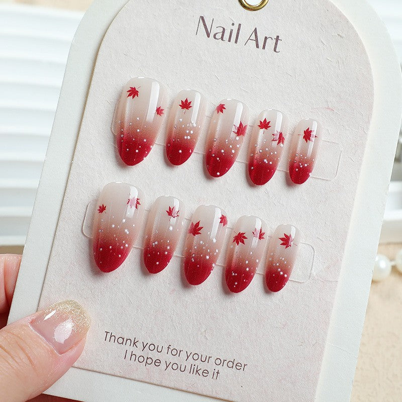 Kunstnagelset mit elegantem Rot-Ombré-Look und zarten Ahornblättern Karnz