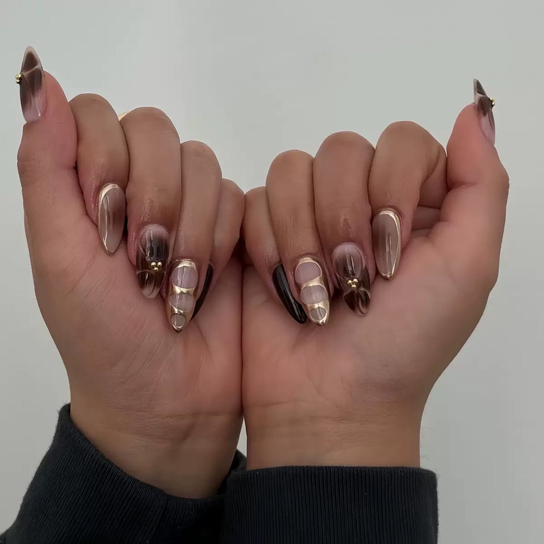 Kunstnagelset mit eleganten Ombre-Design und Goldverzierungen Karnz