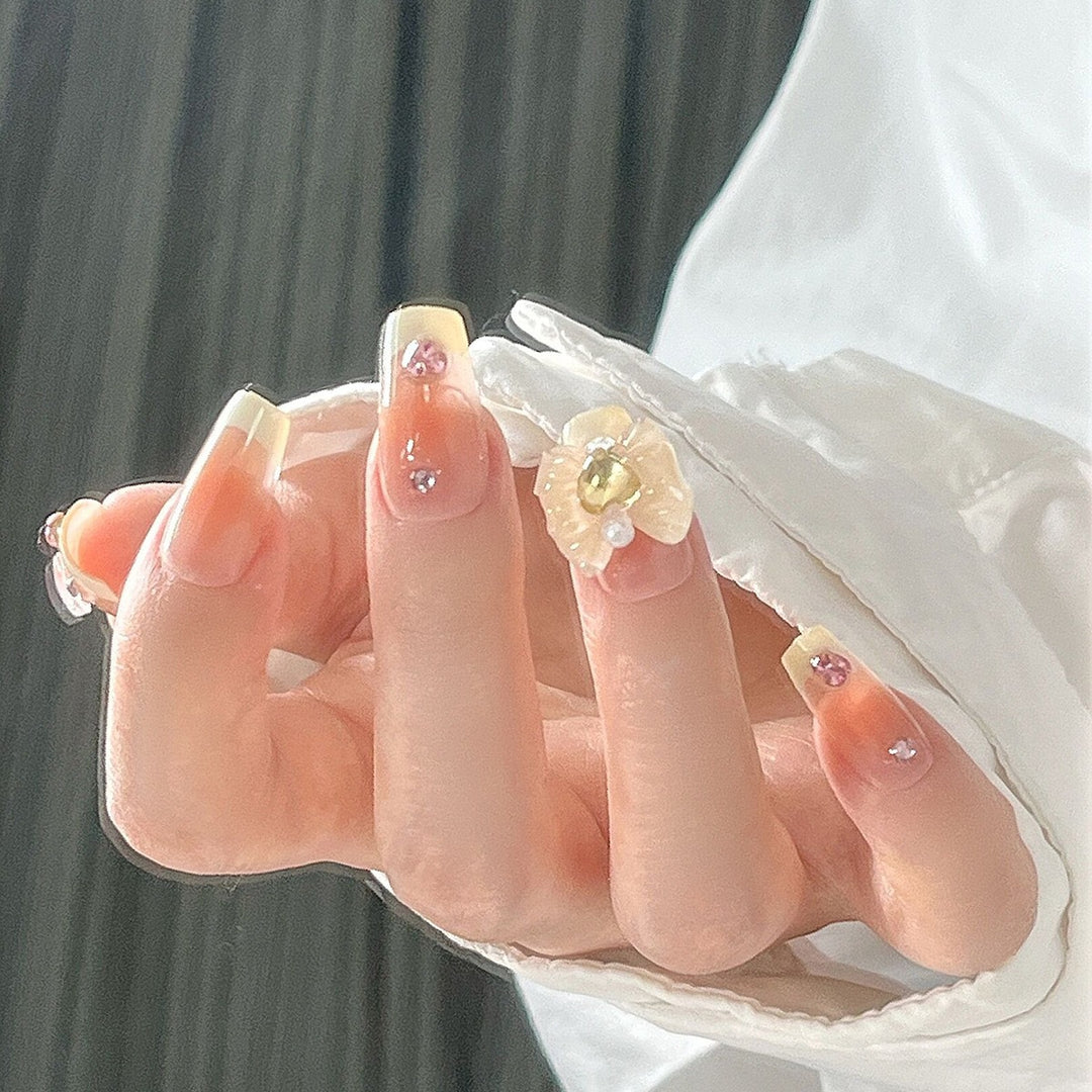 Kunstnagelset mit eleganten Blütenverzierungen und Glitzerakzenten Karnz
