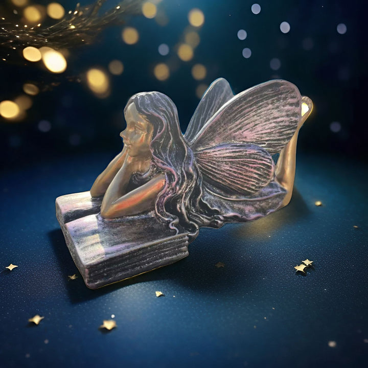 Feenfigurine, die auf Büchern sitzt, Karnz